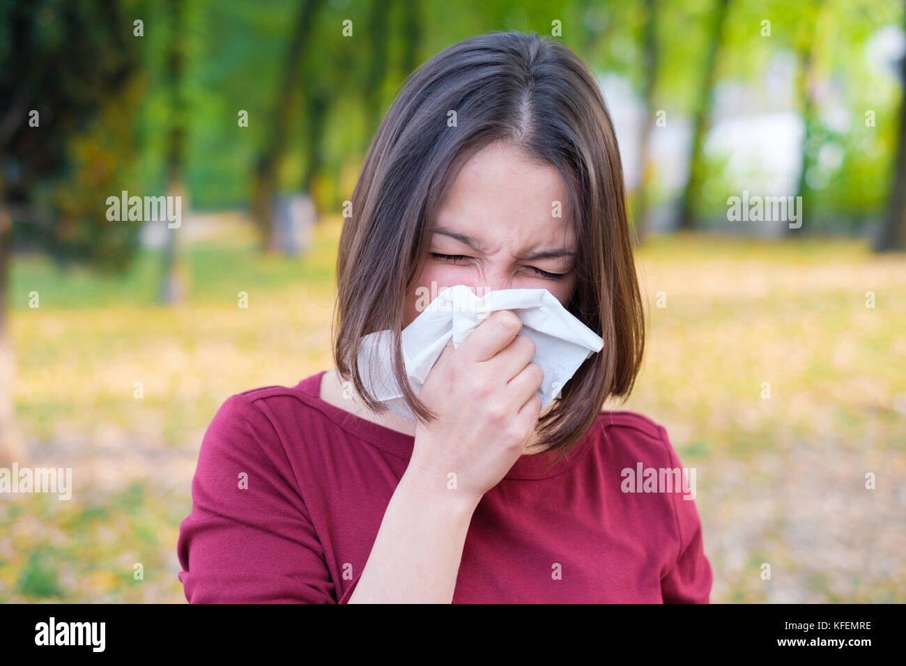 Femme éternuant dans un kleenex à cause d'une allergie saisonnière Banque D'Images