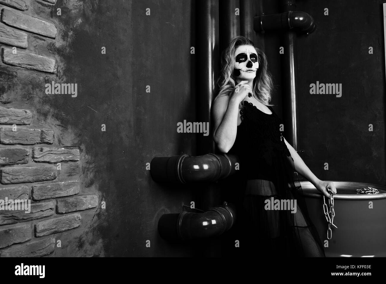 Crâne Halloween maquillage girl porter en noir sur rouge assis sur le baril au studio. Banque D'Images