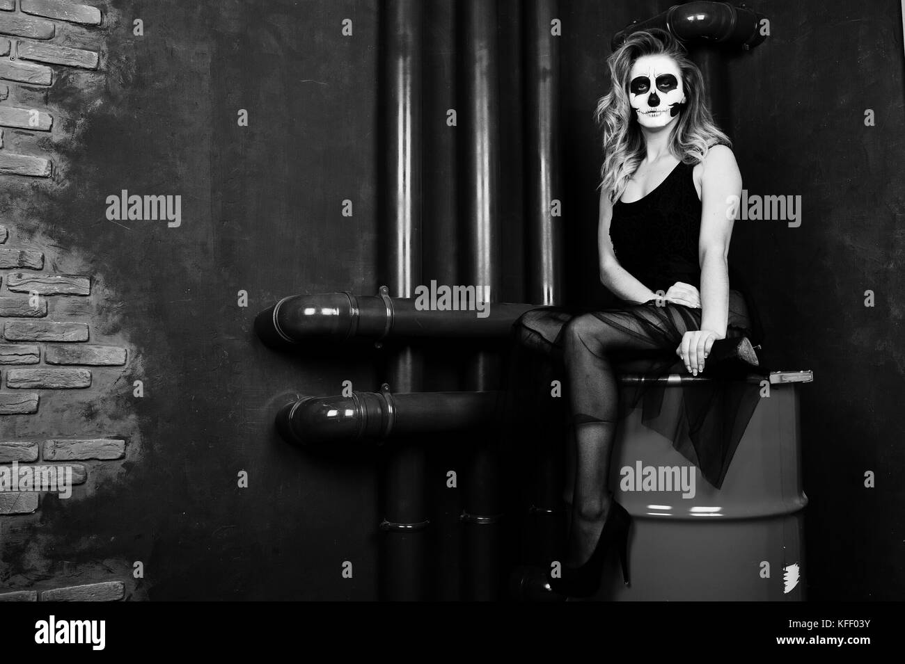Crâne Halloween maquillage girl porter en noir sur rouge assis sur le baril au studio. Banque D'Images