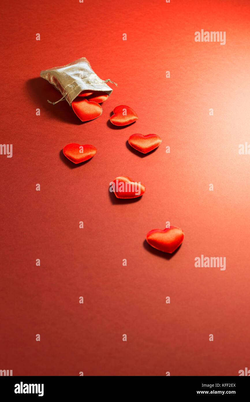 Close-up d'un petit sac rempli d'argent brillant velours rouge mignon coeurs sur fond rouge. concept d'un cadeau d'amour romantique pour les couples, Valentines Day Banque D'Images