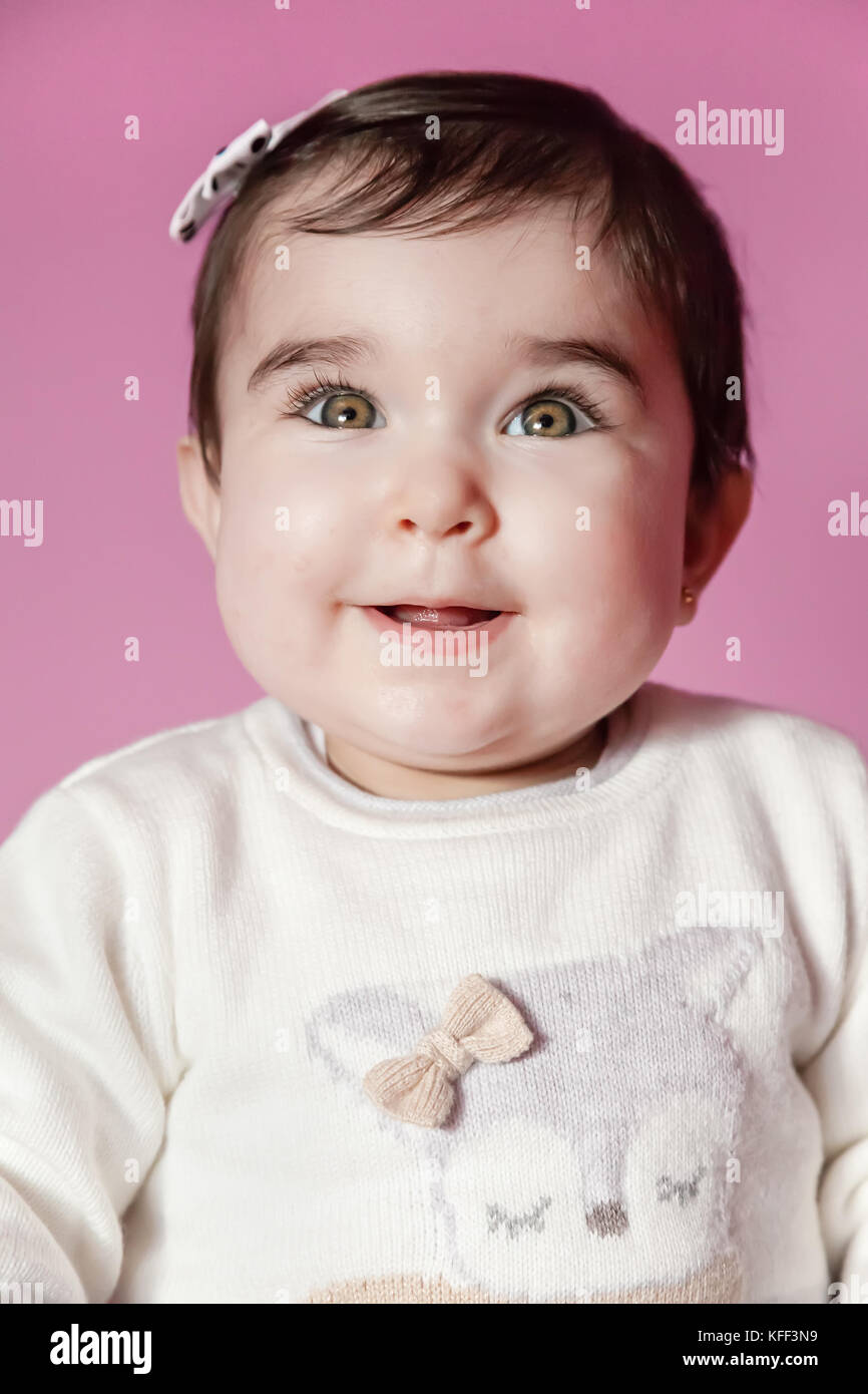 Mignon, joli et happy baby girl smiling portrait portant un arc dans les cheveux. neuf mois / baby girl smiling cute joli sourire heureux chubby amusé Banque D'Images