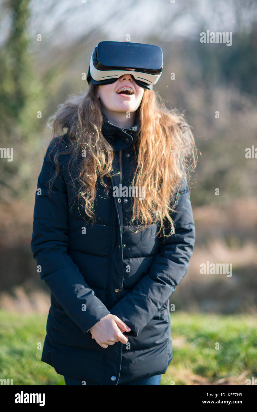 Teenage girl dressed in denim en sunshine portant casque de réalité virtuelle à l'extérieur Banque D'Images