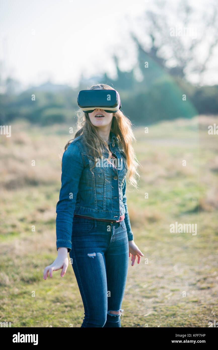 Teenage girl dressed in denim en sunshine portant casque de réalité virtuelle à l'extérieur Banque D'Images