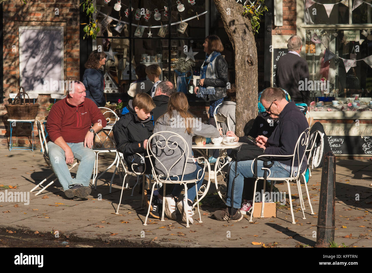 Tables et chaises à l'extérieur de la rue café, les gens en vacances profiter du soleil d'automne, assis, se détendre, prendre des rafraîchissements - College Street, York, Angleterre, Royaume-Uni Banque D'Images