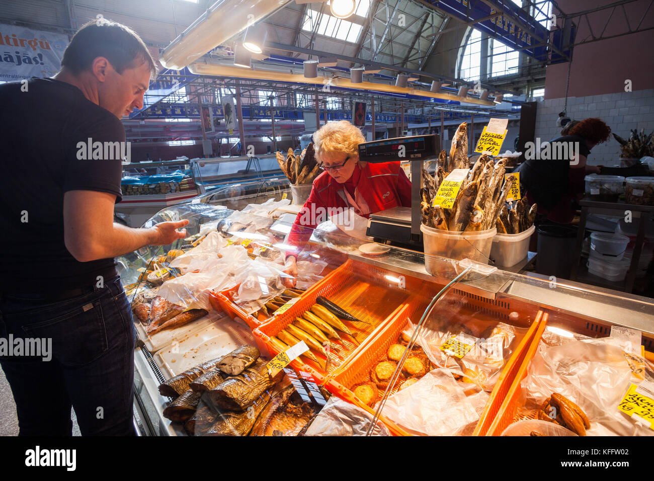 Vendeur de poisson négocie avec un client, marché central de Riga Banque D'Images