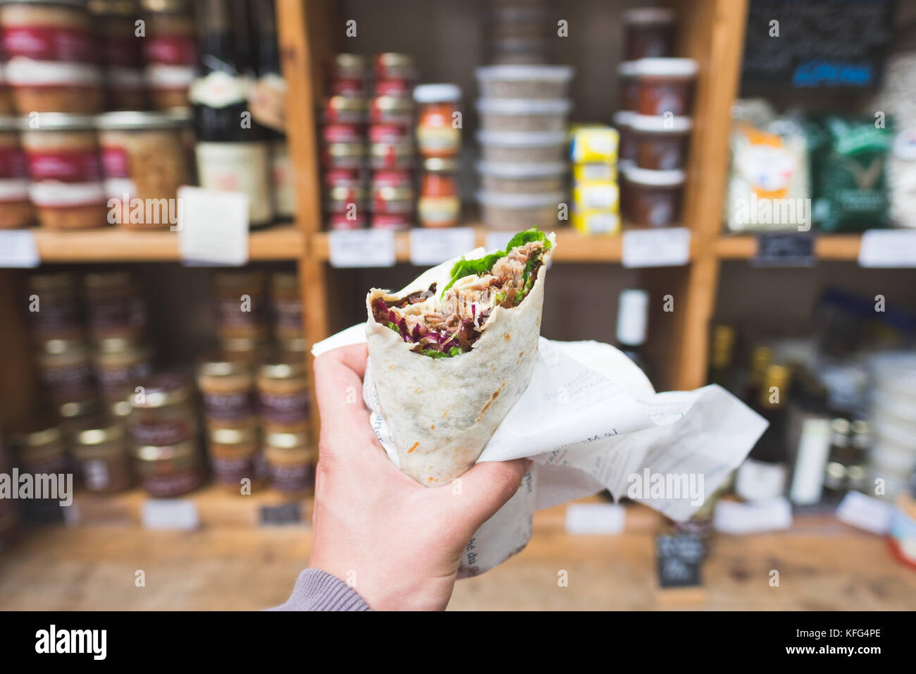 Un confit de canard wrap lieu devant d'autres produits de viande de canard, Borough Market, London Banque D'Images