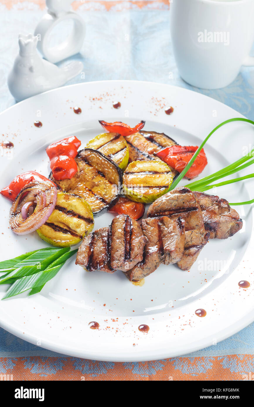 Une viande avec légumes grillés on white plate Banque D'Images
