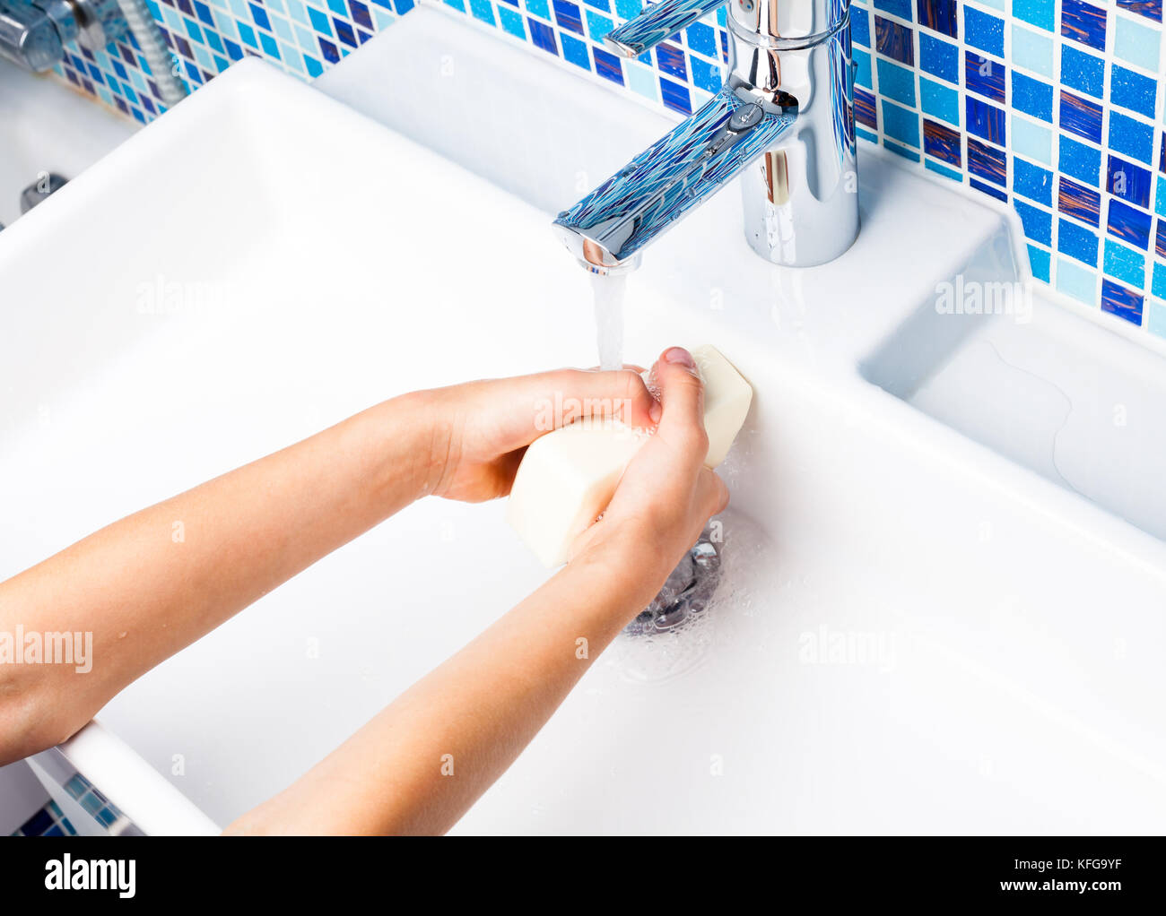 Girl laver ses mains avec du savon dans un évier de salle de bains Banque D'Images