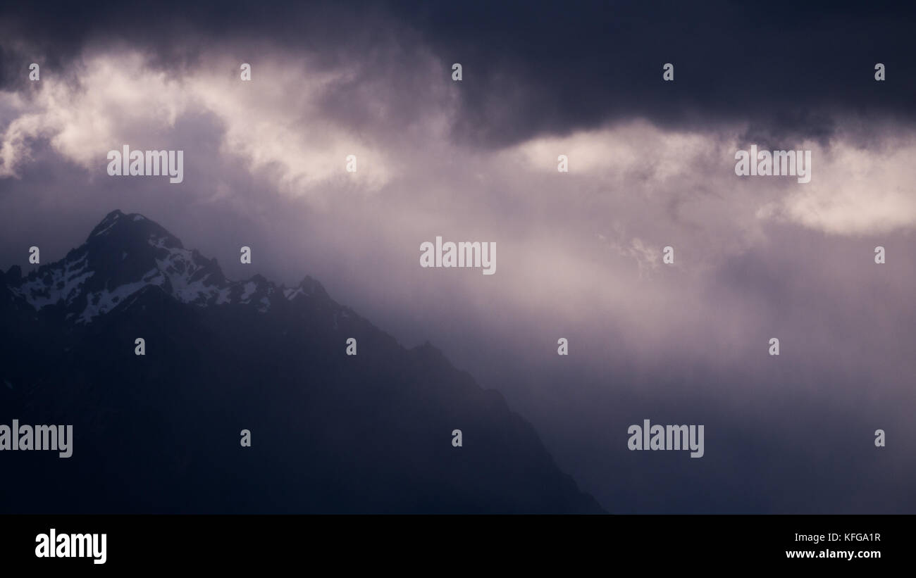 Des faisceaux de lumière à travers les nuages de tempête piercing illuminant snow clad patagonie des pics de montagne au lago Nahuel Huapi à Bariloche Banque D'Images