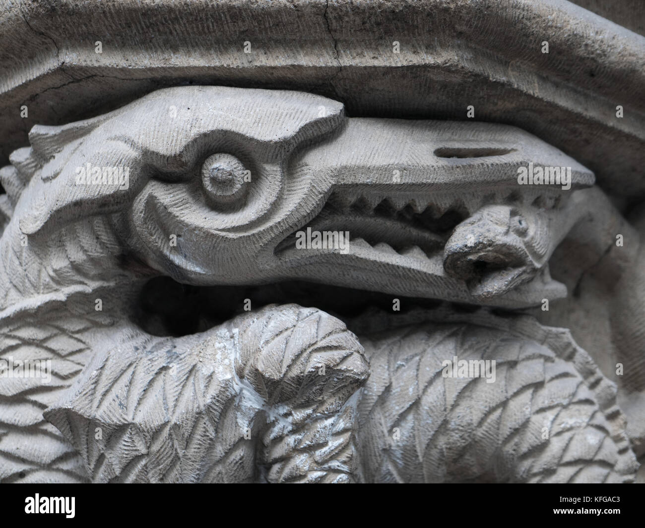 Close up of stone carved bird like avec bec avec des rangées de dents acérées tenant un serpent dans son bec. Banque D'Images