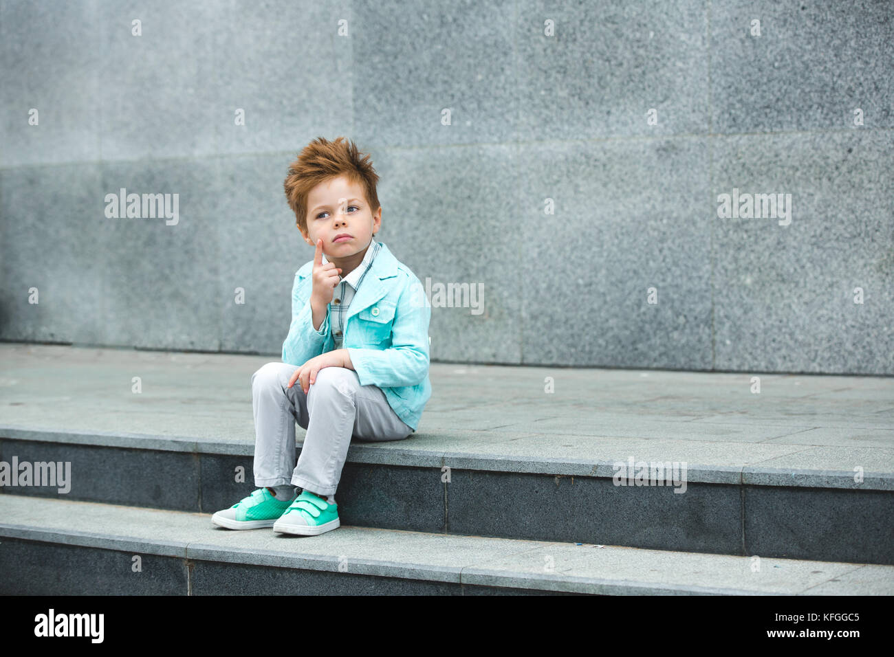 Fashion kid posant près de mur gris Banque D'Images