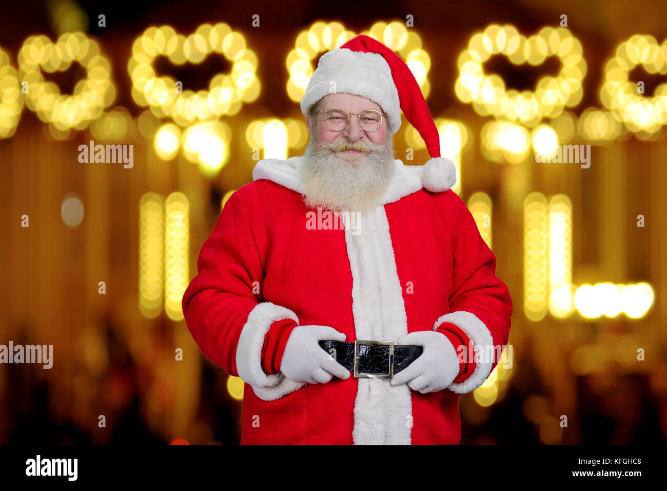 Père Noël authentique sur fond flou réaliste. Le père Noël avec les mains sur la ceinture de sécurité, la nouvelle année de guirlandes arrière-plan. Banque D'Images