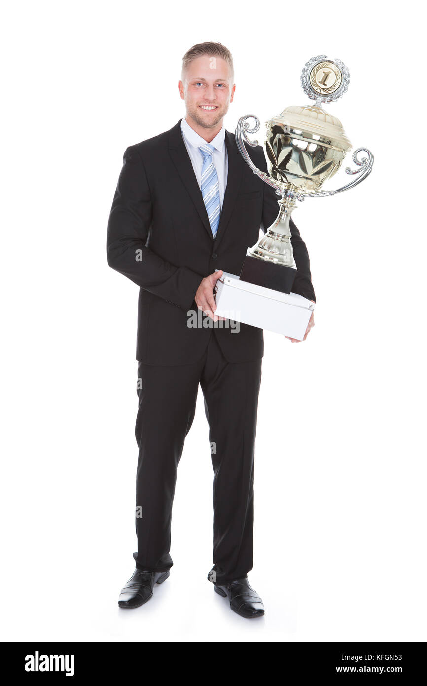 Les barbus élégant businessman holding un grand trophée d'argent dans ses mains afin de récompenser ses réalisations ou d'une victoire dans une compétition on white Banque D'Images