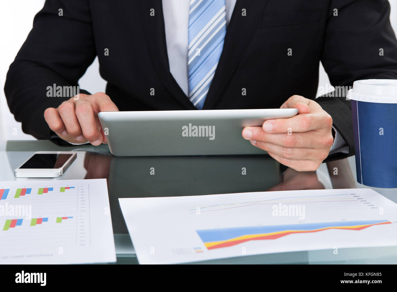 Mains d'un homme d'affaires à l'aide d'un ordinateur tablette tout en étant assis à son bureau de l'analyse graphique Banque D'Images