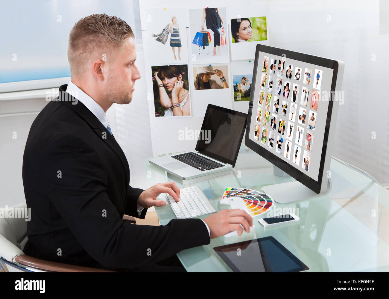 Businessman assis à son bureau en face d'un moniteur à grand écran photographies édition Banque D'Images
