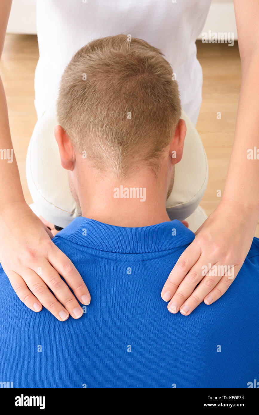 Man receiving shoulder massage par female therapist Banque D'Images