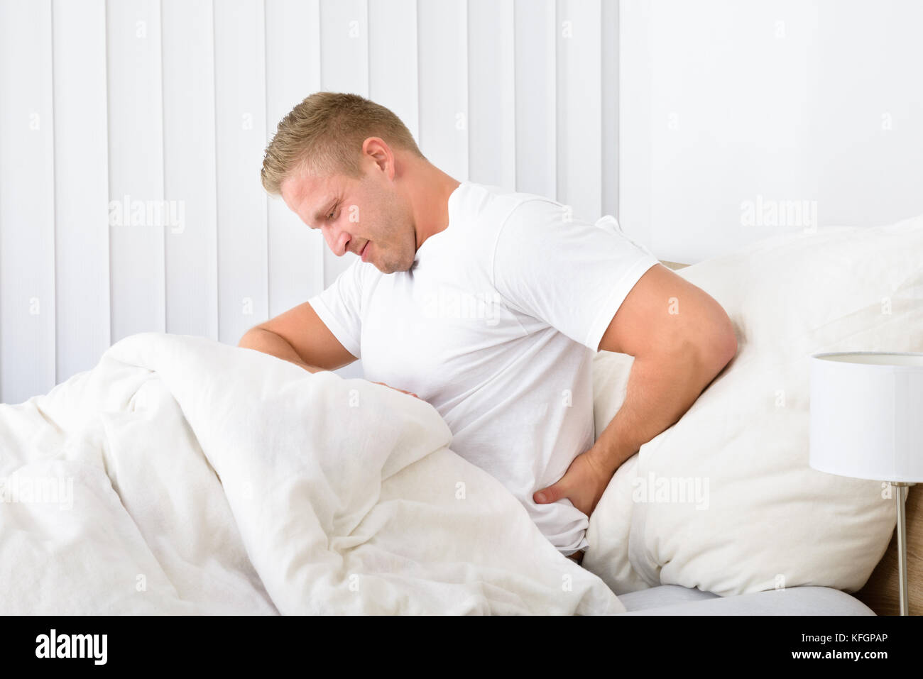 Portrait de jeune homme assis sur le lit de souffrance backpain Banque D'Images