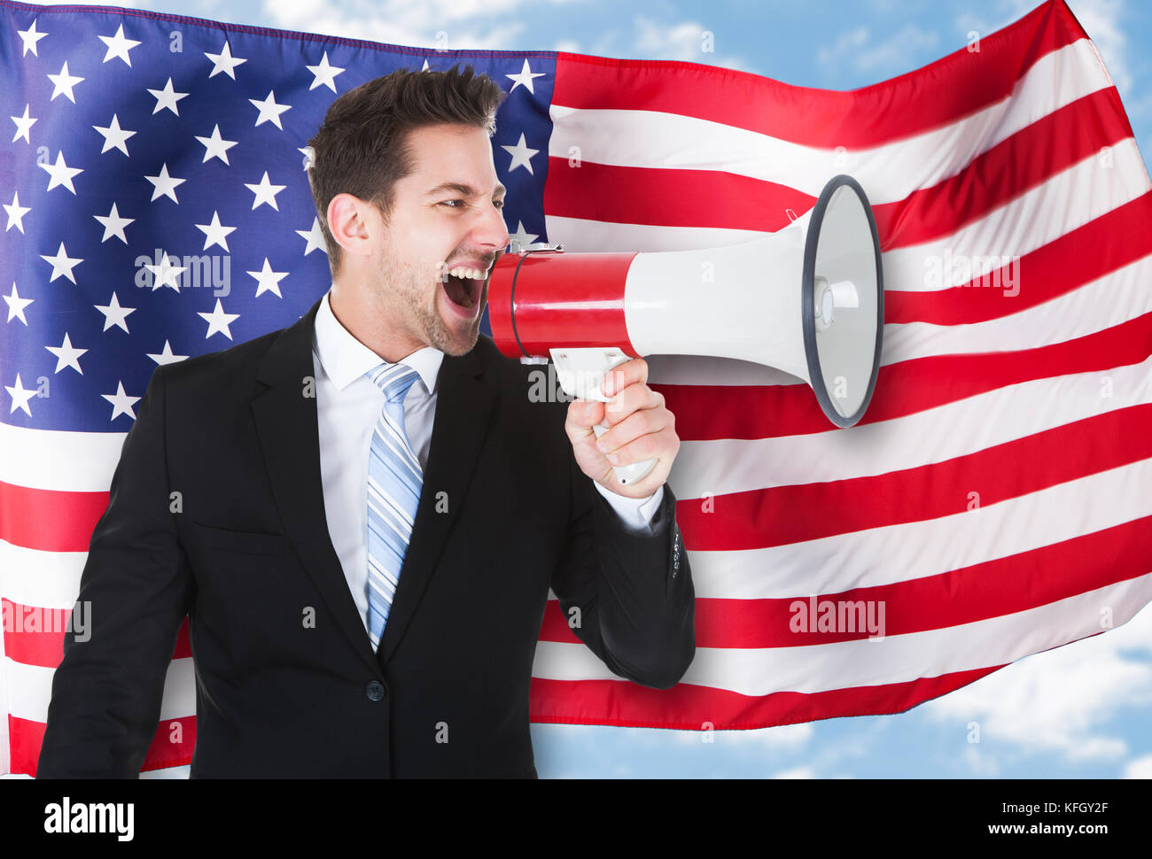 Portrait of a businessman shouting par mégaphone in front of american flag Banque D'Images