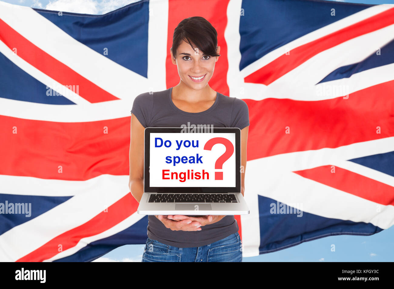 Young woman holding laptop poser parlez-vous français en face de drapeau britannique Banque D'Images