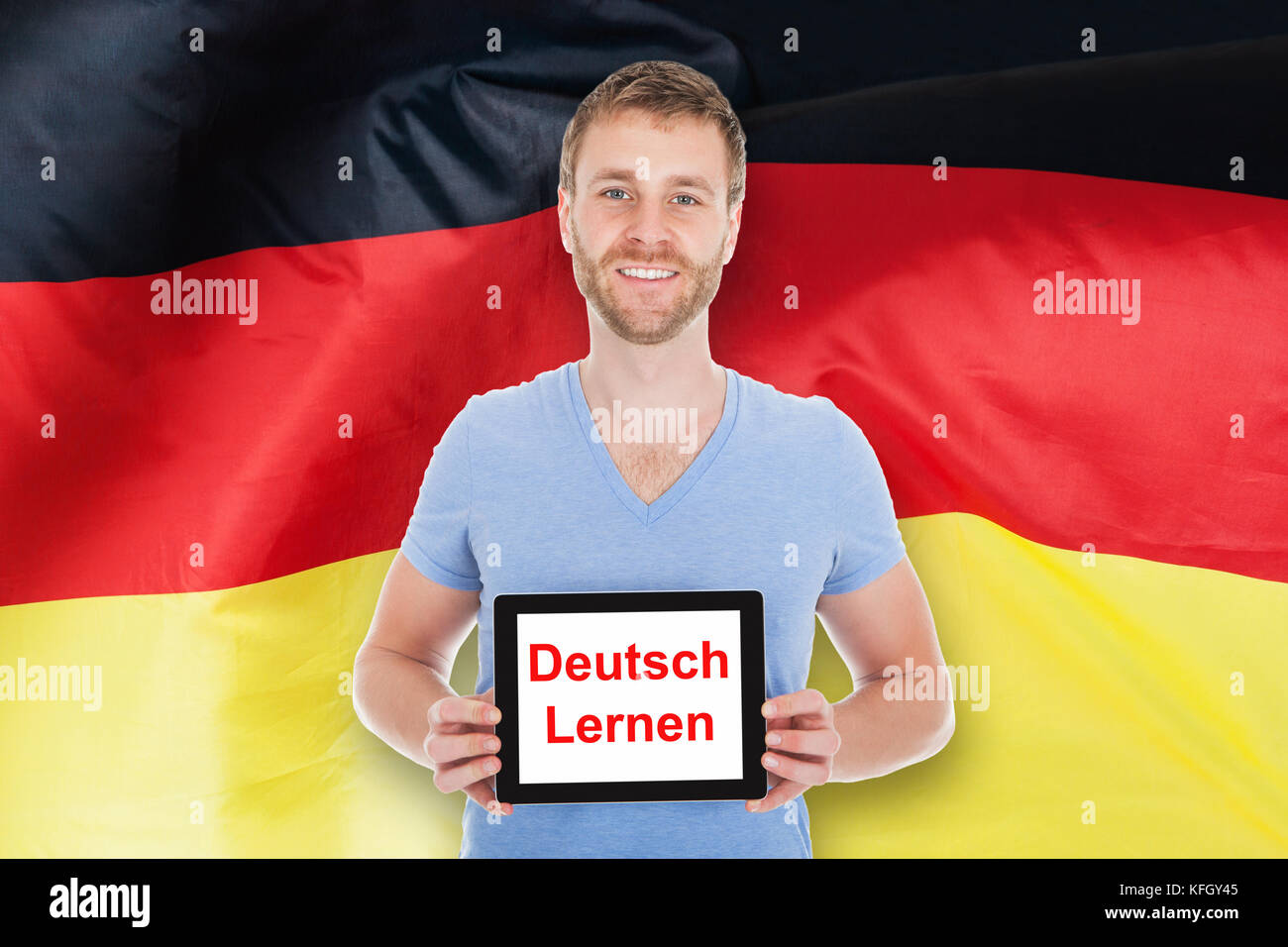 Jeune homme en face de l'Allemagne flag holding digital tablet avec apprendre texte allemand Banque D'Images