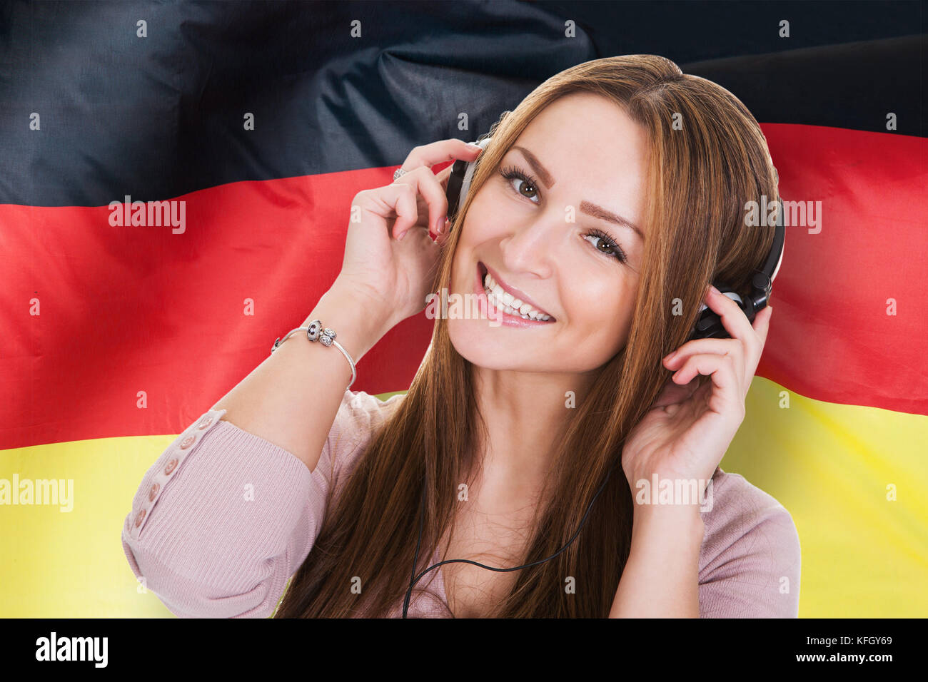 Femme à l'écoute de livres audio d'apprentissage allemand en face de drapeau allemand Banque D'Images