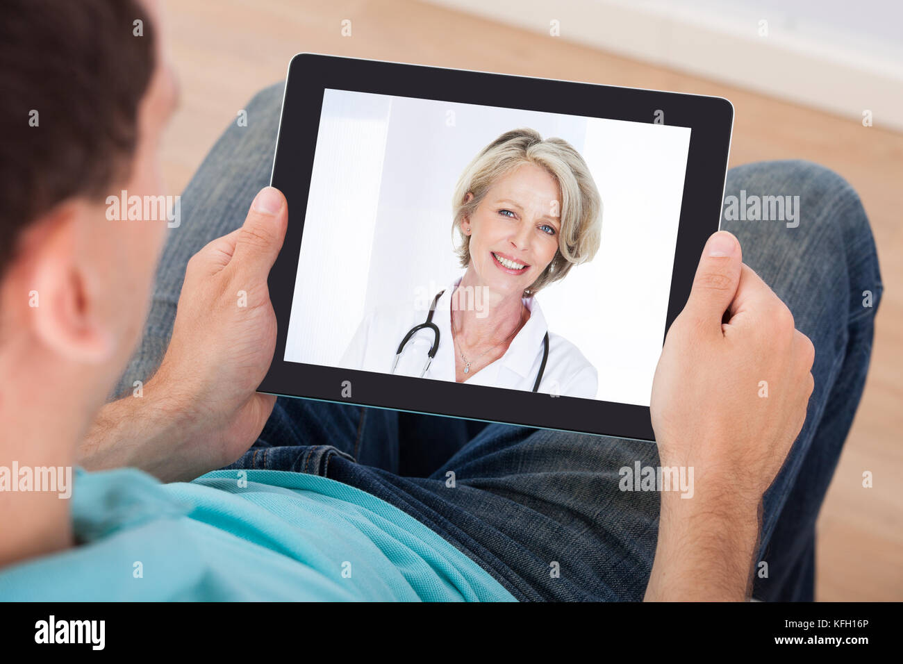 L'homme ayant une conversation vidéo avec femme médecin sur digital tablet Banque D'Images