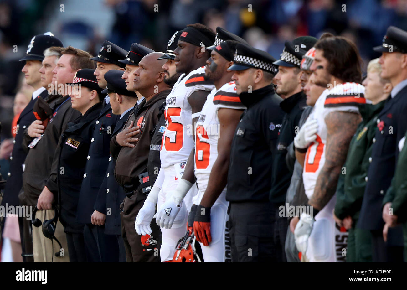L'entraîneur-chef des Cleveland Browns, Hue Jackson (au centre à gauche), se dresse avec des joueurs et des membres des services d'urgence lors de l'hymne national avant le match de la NFL International Series à Twickenham, Londres. Banque D'Images