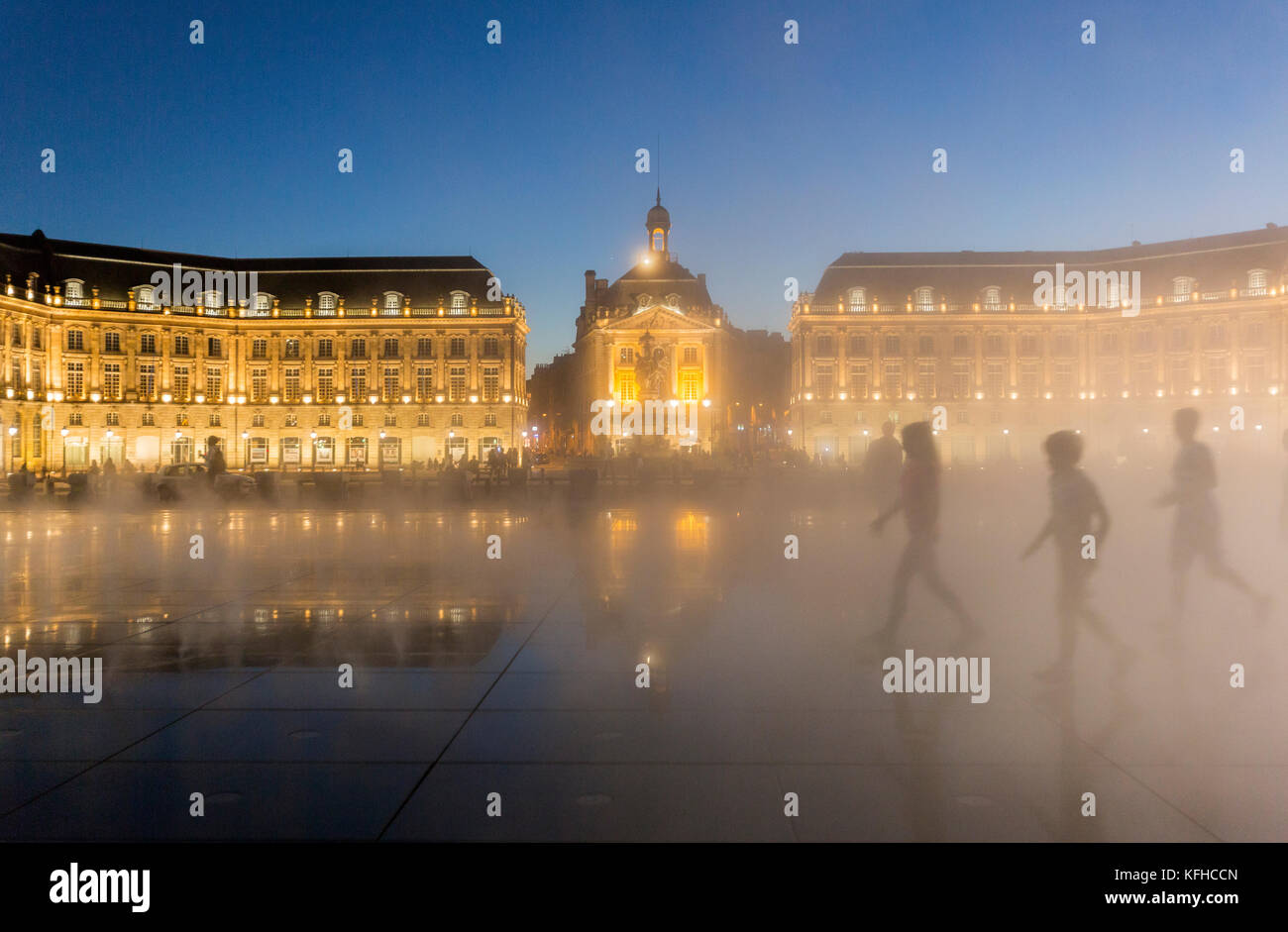 Les silhouettes de gens dans Water Mirror, le miroir d'eau, la plus grande piscine de réflexion du monde la nuit à la place de la Bourse, Burdeaux, France Banque D'Images