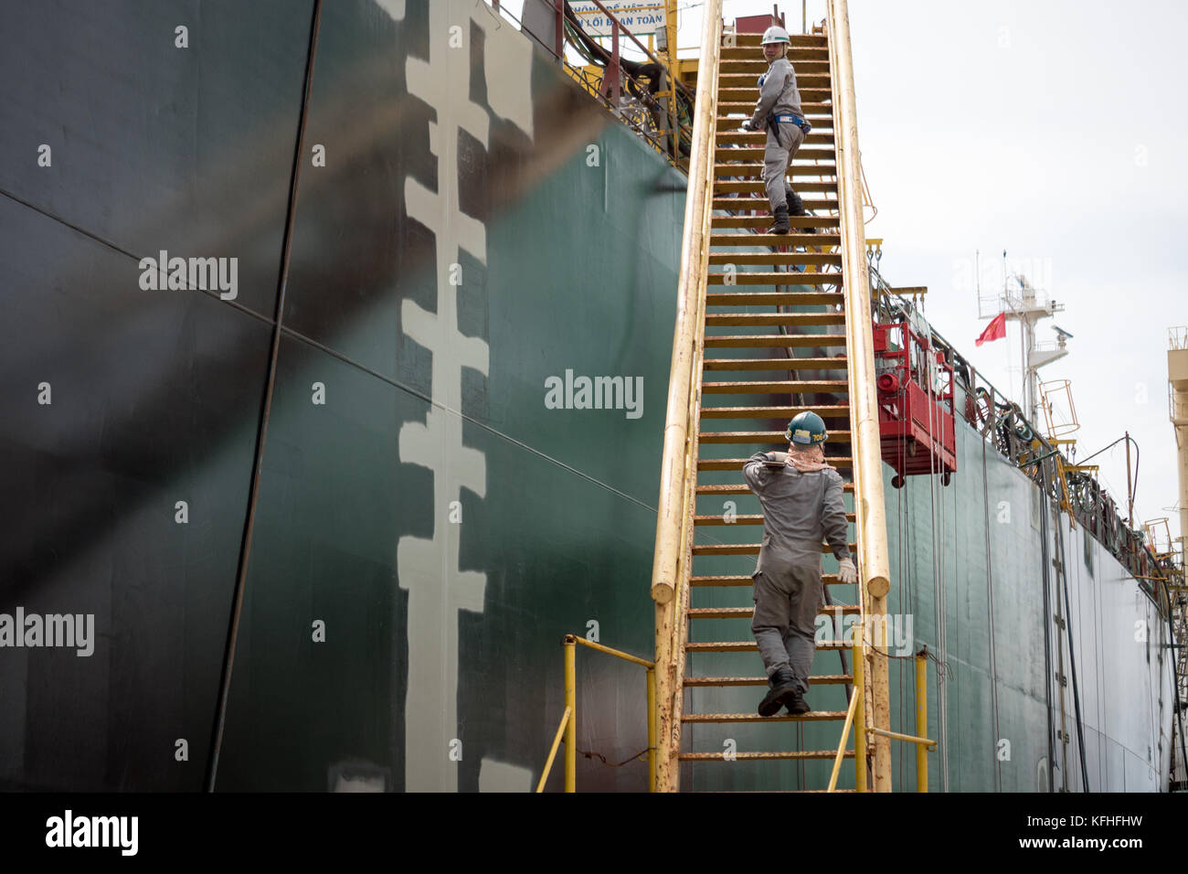 Deux travailleurs aller vers le haut de l'échelle à bord du navire en construction. cam rahn shipyard, Vietnam. Banque D'Images