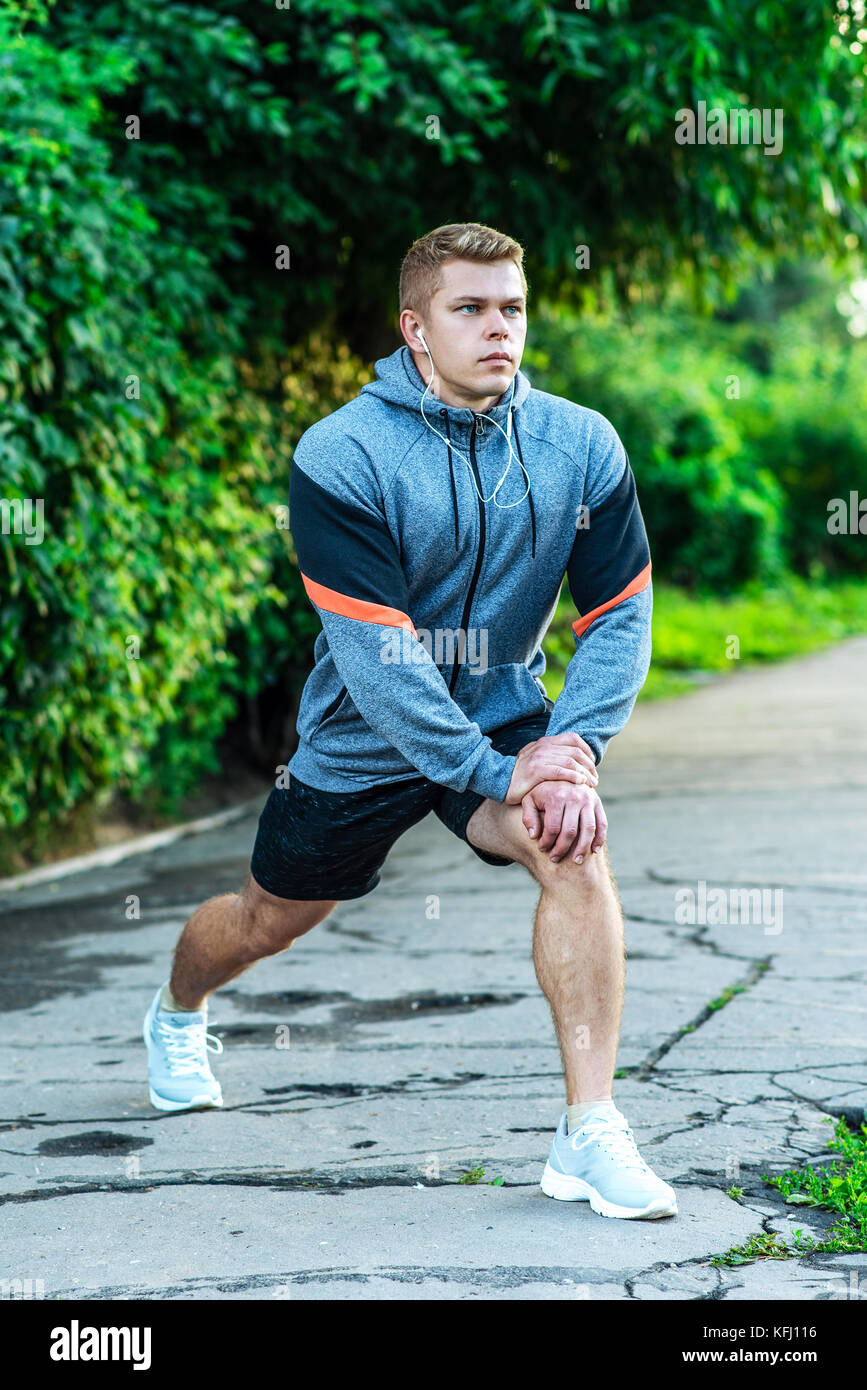 Un homme dans le parc dans le cadre d'un échauffement. Écoute de la musique pour une promenade dans la ville. Athletic mode de vie. Banque D'Images