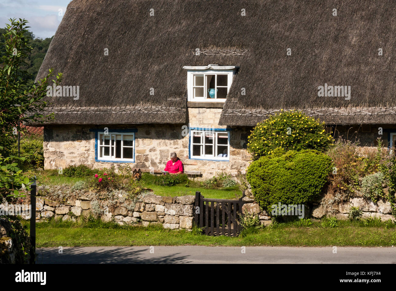 Une dame se détend, la lecture, en dehors de sa chaumière à Rievaulx,North Yorkshire, Angleterre, Royaume-Uni Banque D'Images