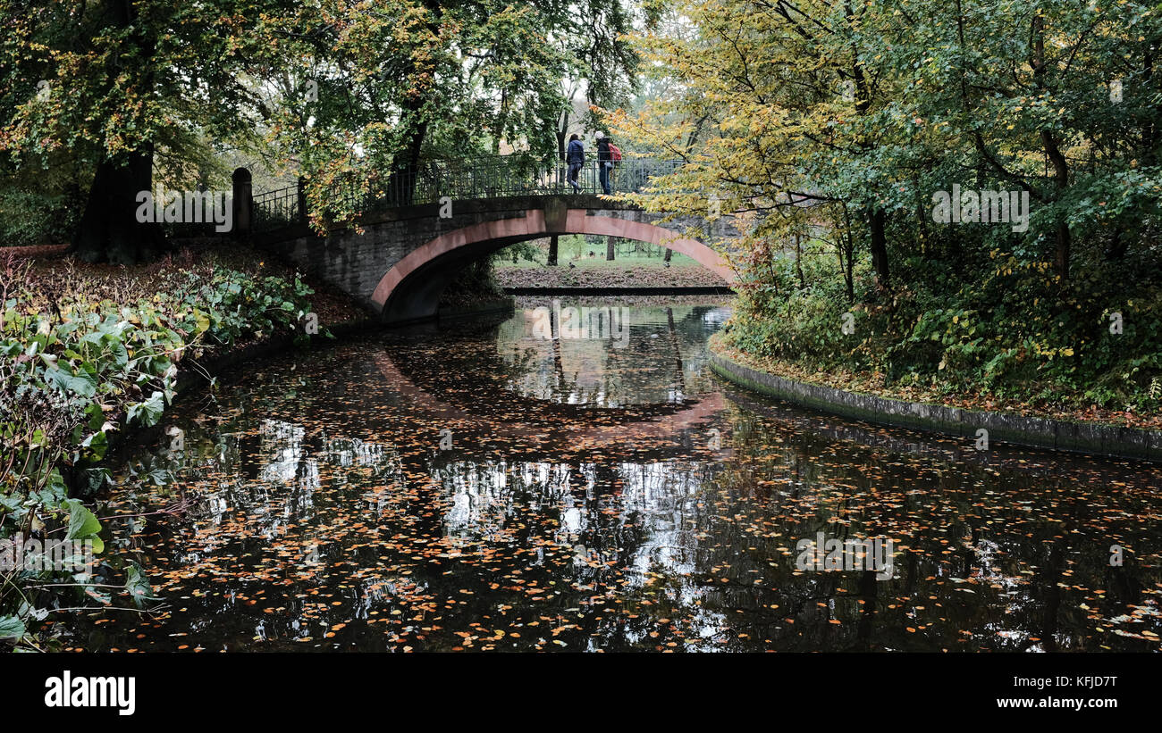 Deux marcheurs traverser un pont bénéficiant d couleurs d'automne dans les jardins de Frederiksberg, danemark Banque D'Images