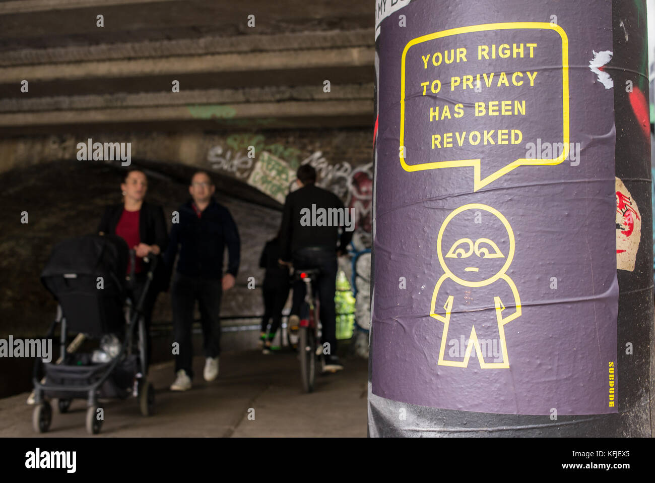 Street art poster accroché sur un tunnel près de la colonne de l'artiste subdude avec homme stylisé et cartoon avec slogan "Votre droit à la vie privée a été révoquée". Banque D'Images