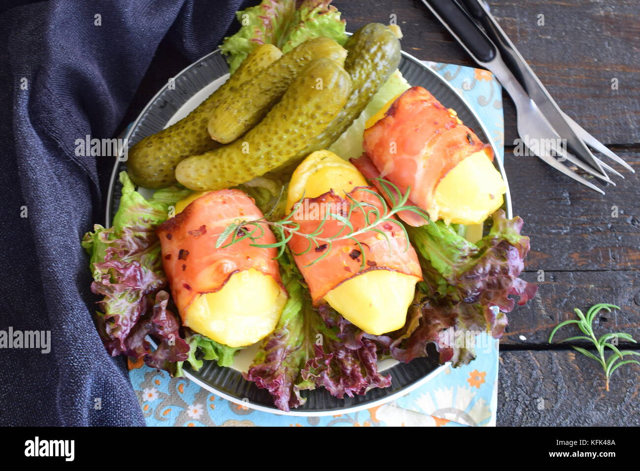 Pomme de terre cuite au four avec du fromage enrobé de bacon, servi avec des légumes marinés. Banque D'Images