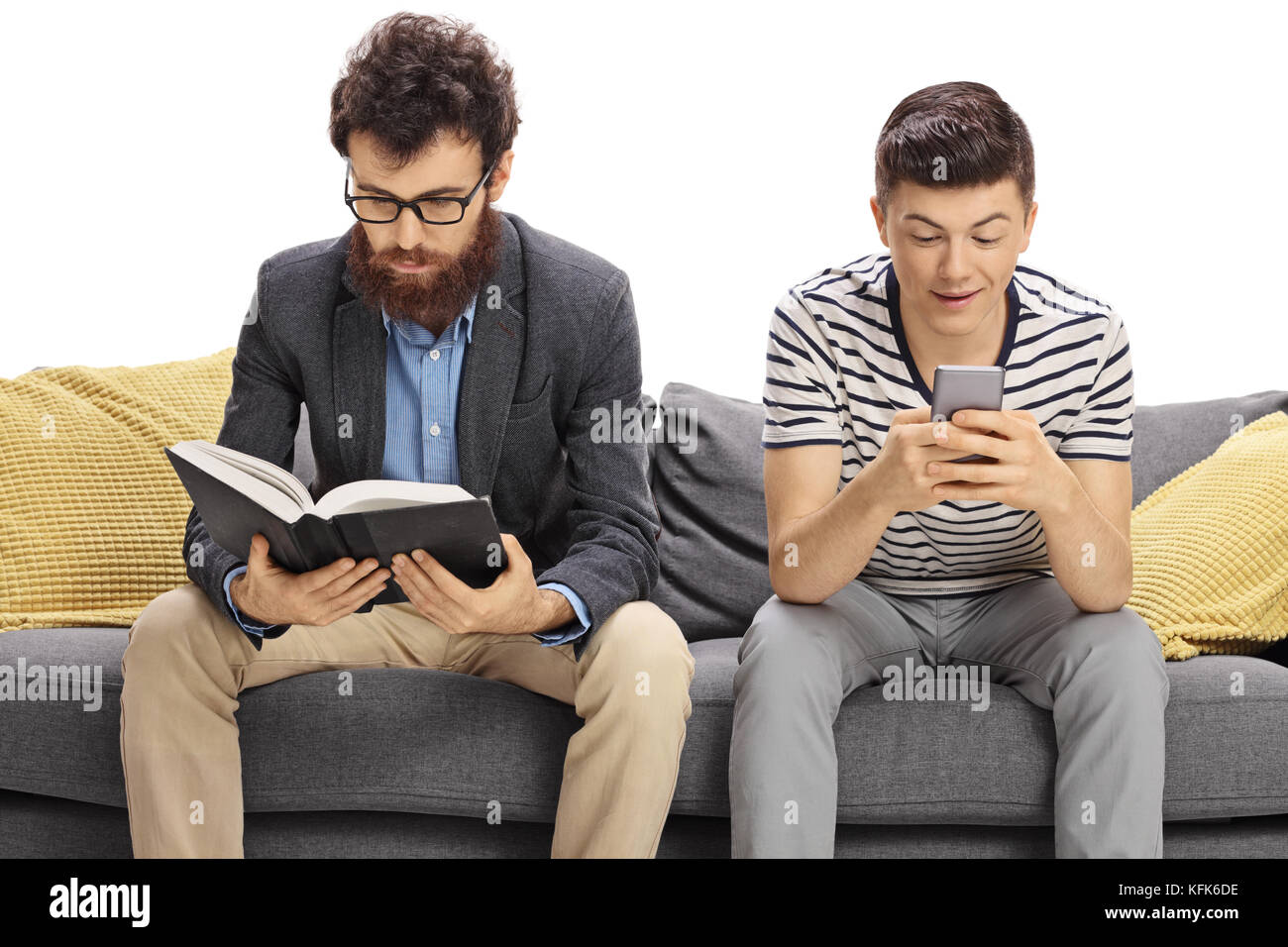 Père assis sur un canapé-lit un livre avec son fils adolescent assis à côté de lui et en regardant un téléphone isolé sur fond blanc Banque D'Images