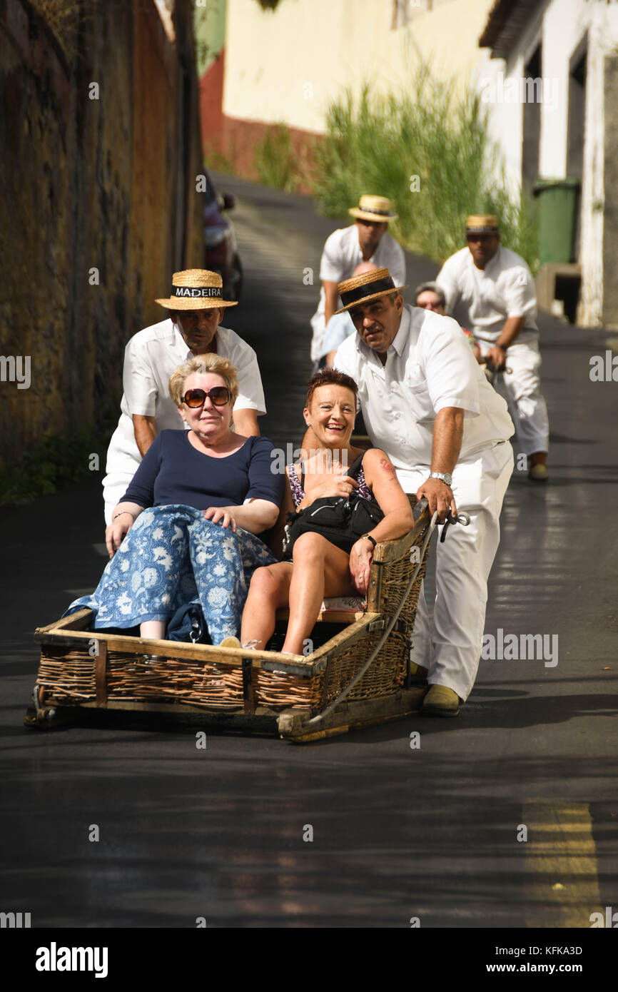 Madère, Portugal - septembre 2017 : les touristes de prendre une descente en toboggan traditionnel panier en osier Banque D'Images