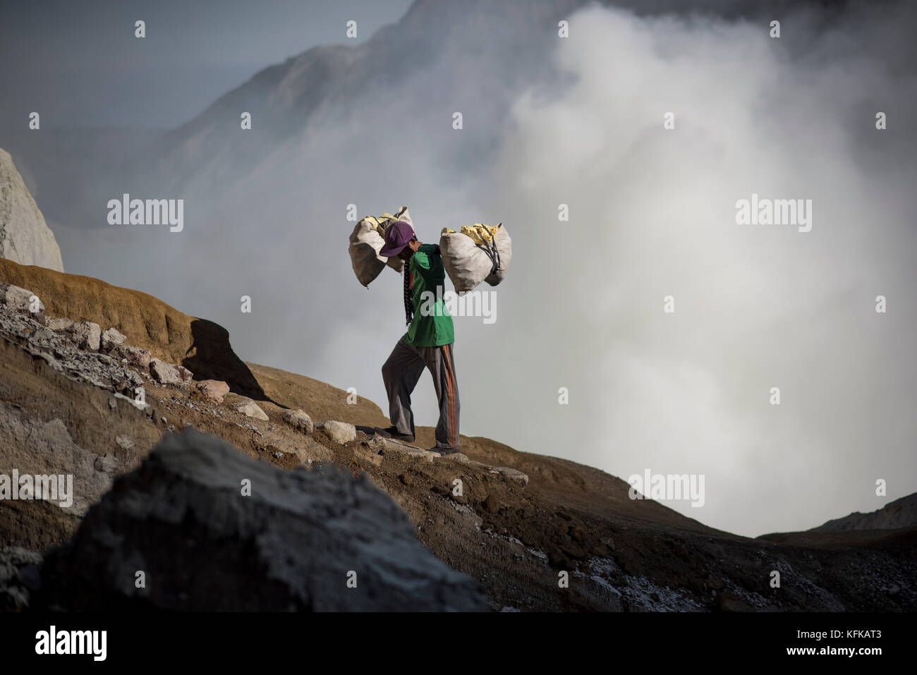 Mineur de soufre Soufre transportant les rochers jusqu'au sommet du cratère du kawah ijen, java, Indonésie. Banque D'Images