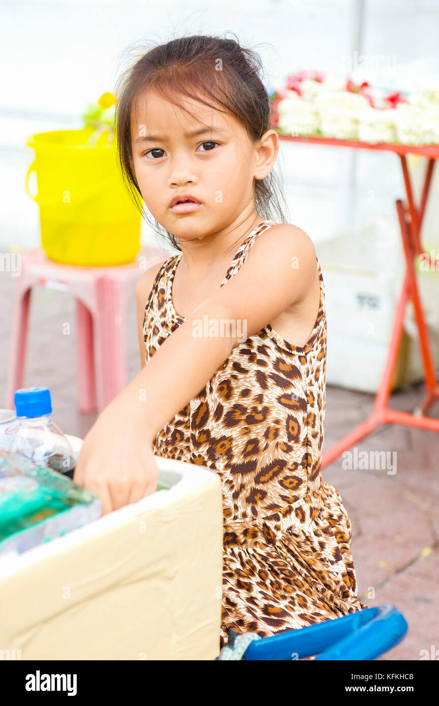 Un peu thai girl aide ses parents vendent l'eau et des rafraîchissements dans un temple à Bangkok, Thaïlande. Banque D'Images