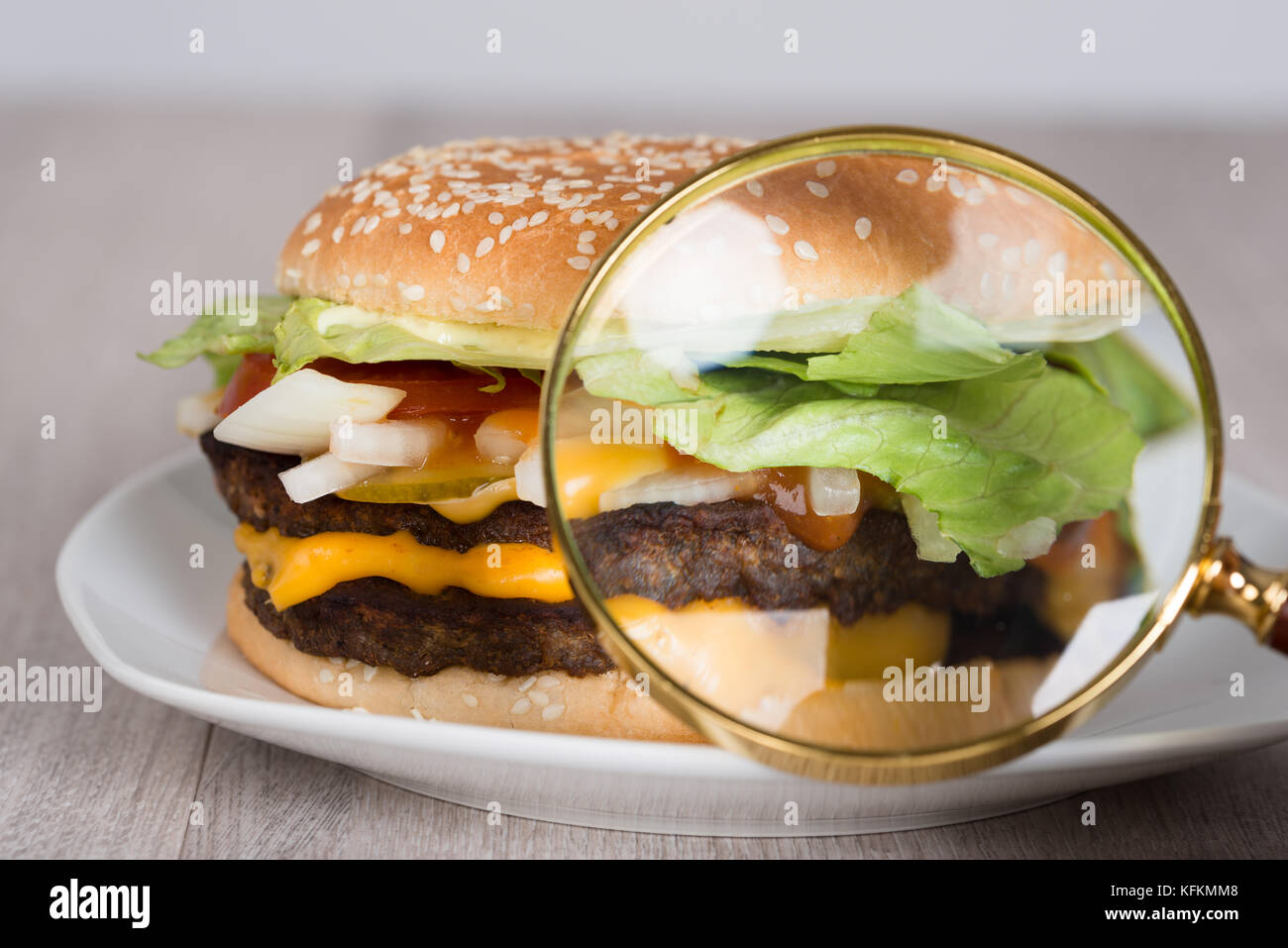Gros plan de la loupe examinant le hamburger dans la plaque Banque D'Images