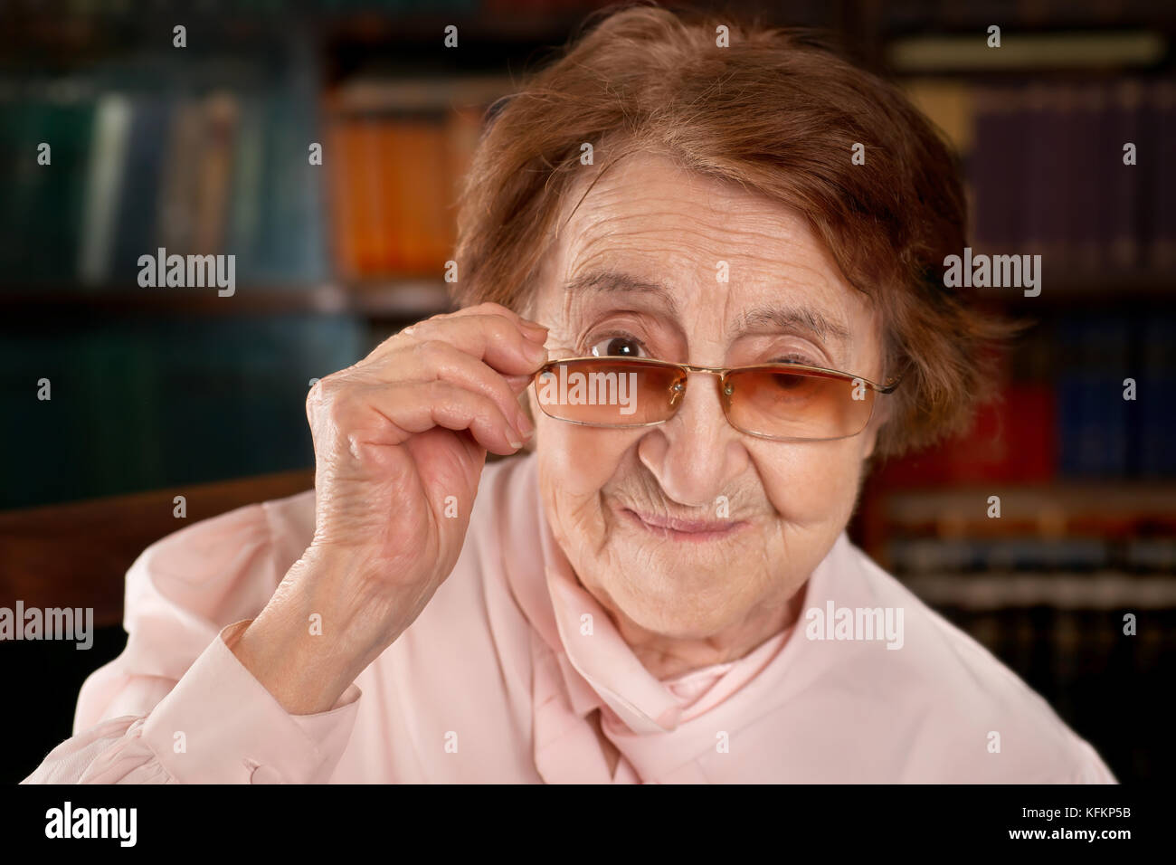 Hauts smiling woman looking over les lunettes. selective focus sur fond bibliothèque vintage. Banque D'Images