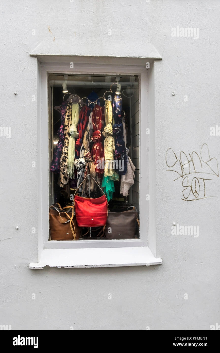 Un petit magasin de fenêtre avec un affichage des écharpes et des sacs à main. Banque D'Images