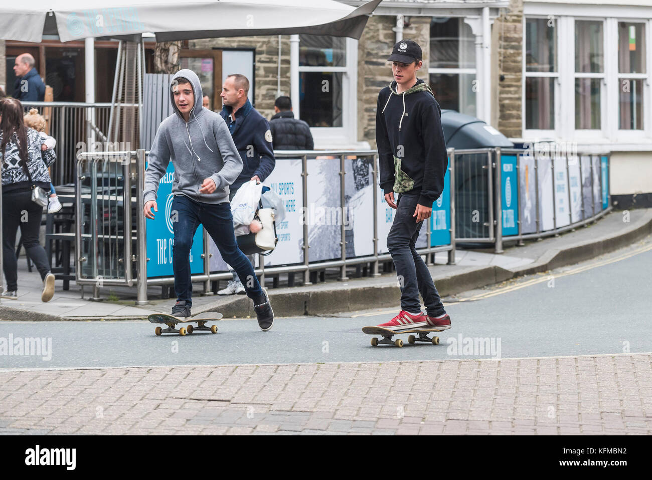 Skateboard - deux adolescents skayeboard le long d'une route publique à Newquay Cornwall. Banque D'Images
