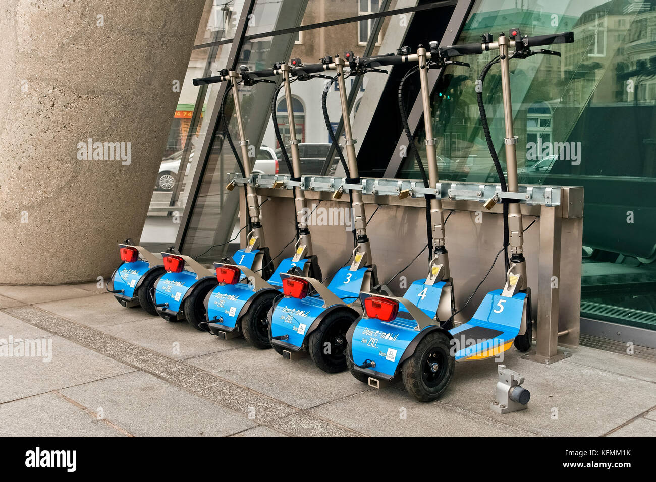 Compagnie d'UNICA scooters électriques jetables pousser garée à côté de l'édifice du siège social de la porte. Eco friendly. Vienne Vienne, Autriche, Europe Banque D'Images