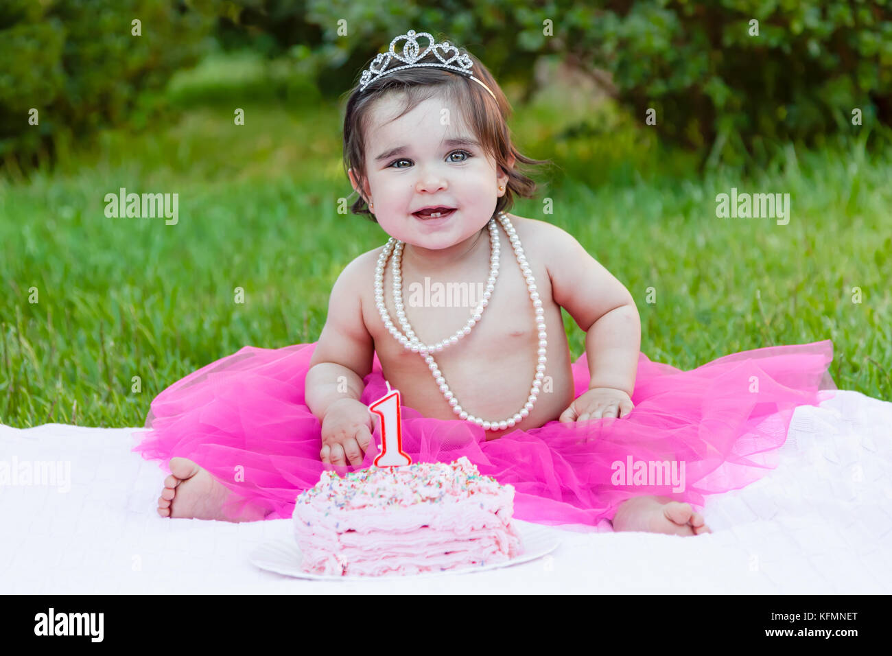 Smiling happy baby girl en première fête gâteau rose avec piscine. habillé avec princess tiara, collier de perle, tutu pour anniversaire Banque D'Images