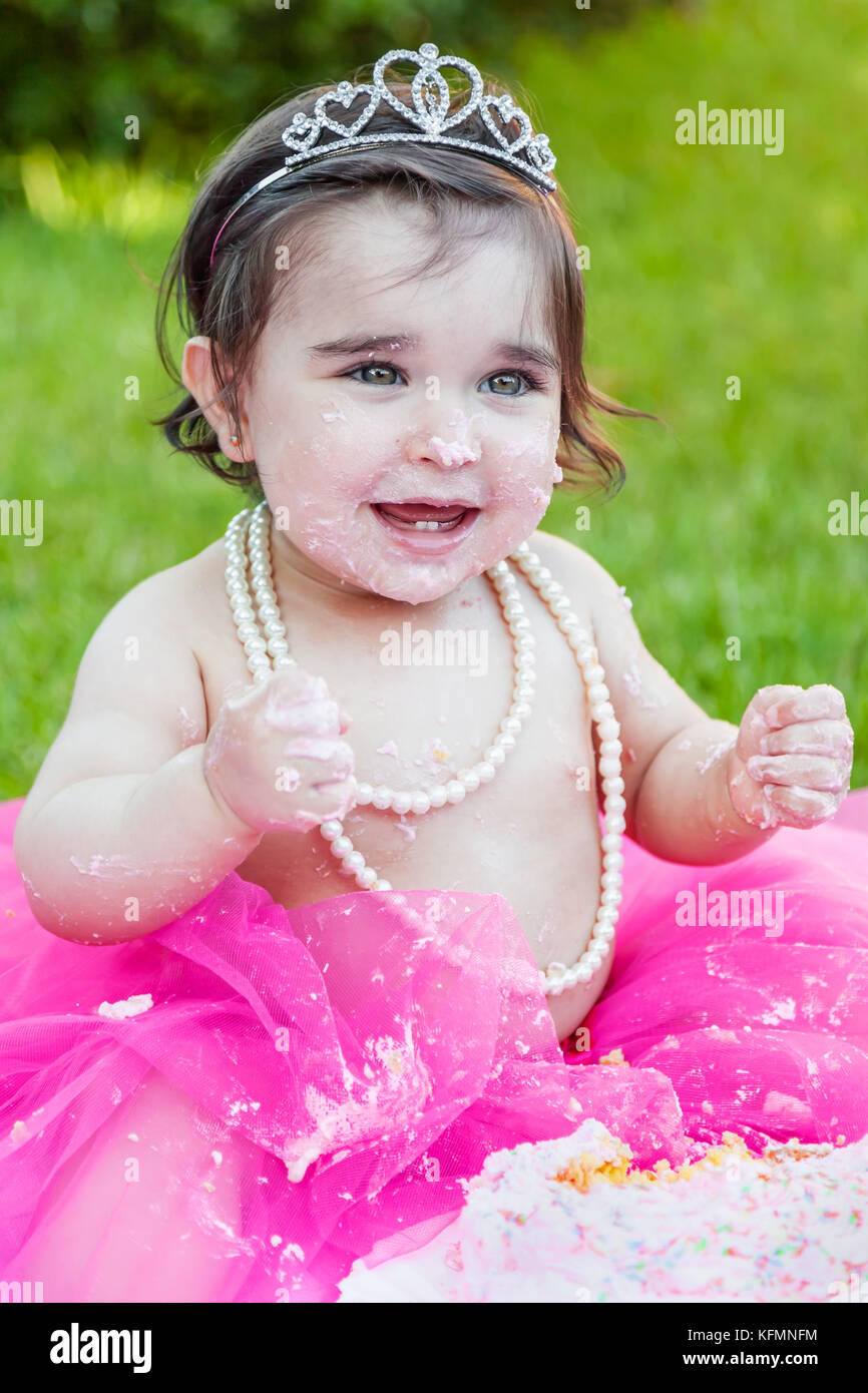 Smiling happy baby girl premier anniversaire anniversaire partie. rire avec visage et mains sales de gâteau rose fracassées. princess tiara costume Banque D'Images