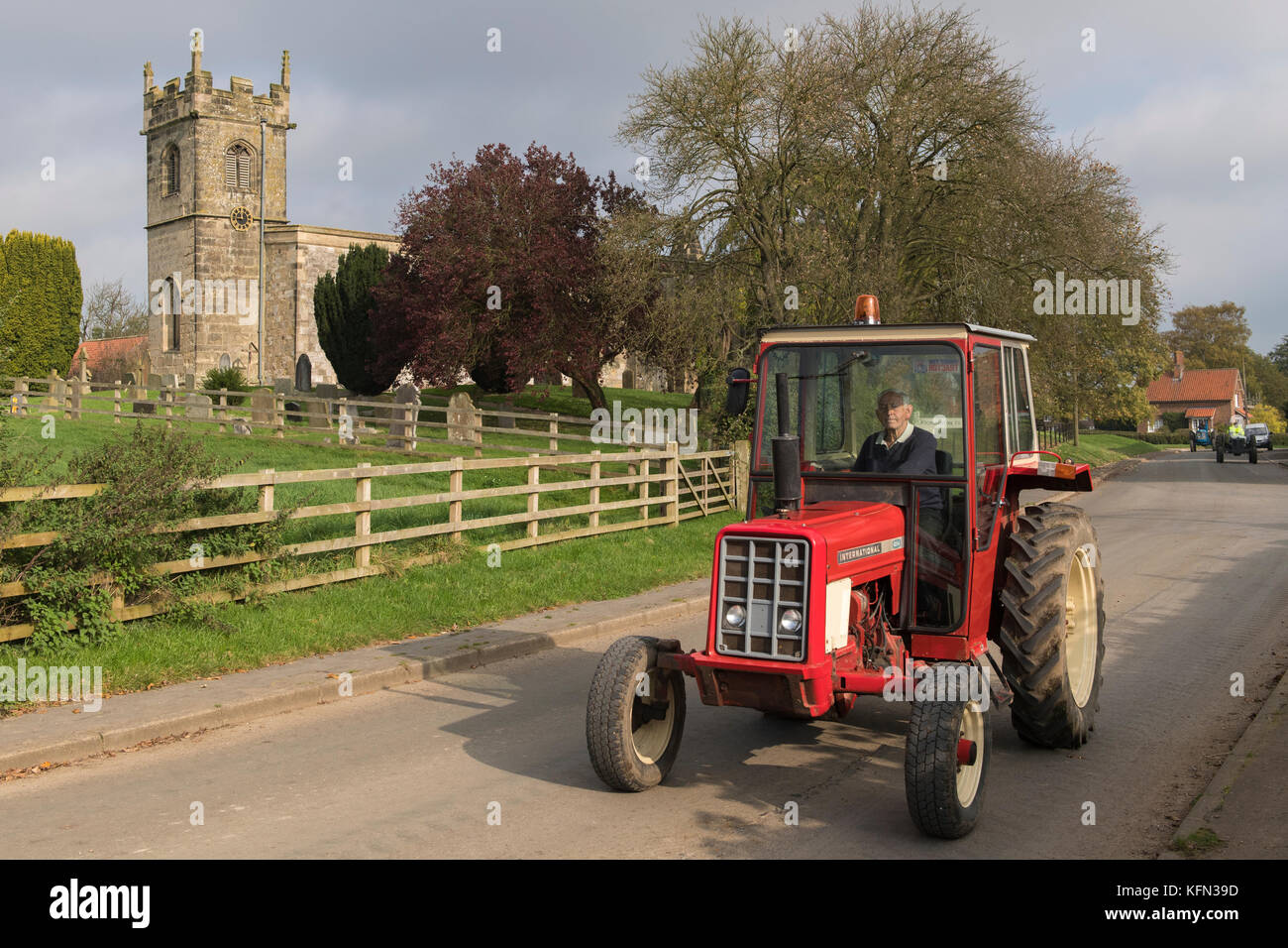 Man driving old red vintage tracteur au travers de village Bugthorpe sur Wolds Vintage Group Cours sur la route, un événement annuel de bienfaisance - Yorkshire, Angleterre, Royaume-Uni. Banque D'Images