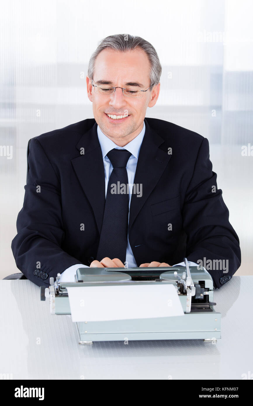 Portrait of mature businessman typing sur machine à écrire Banque D'Images