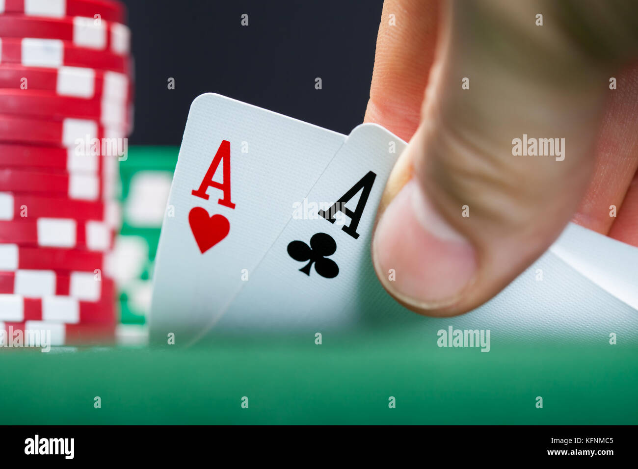 Close-up of male poker player soulevant les bords de deux cartes Banque D'Images