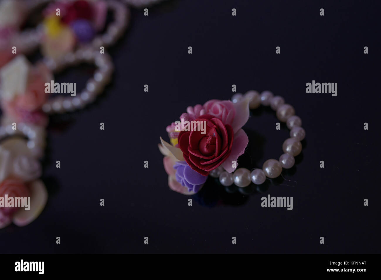 Bracelet avec perles ludiques en cuir et en matière plastique, des ornements floraux sur une surface sombre avec selective focus Banque D'Images