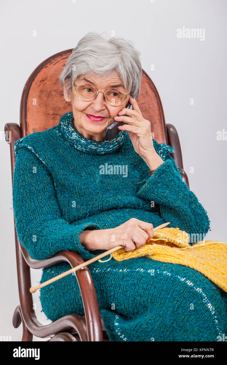 Portrait d'une vieille femme avec des outils de tricot et d'utilisation d'un téléphone mobile.expression Banque D'Images